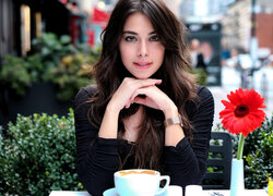 Dziewczyna siedząca przy stole z filiżanką kawy