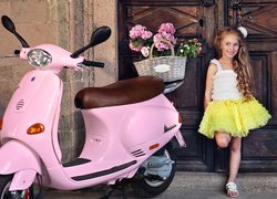 Dziewczynka i różowy skuter z koszem kwiatów