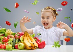 Dziewczynka przy stole z owocami i warzywami
