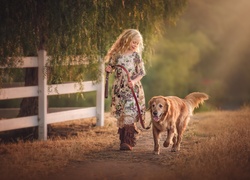 Dziewczynka spaceruje ze swoim psem rasy golden retriever