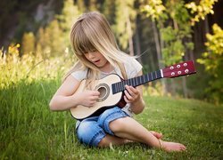 Dziewczynka z gitarą na łące