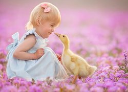 Dziewczynka z kaczuszką wśród różowych kwiatów