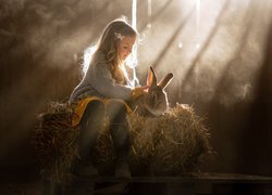 Dziewczynka z królikiem na beli siana
