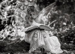 Dziewczynka ze skrzydełkami przegląda książkę