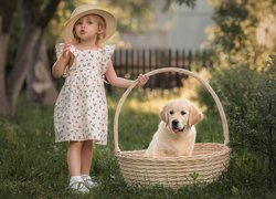 Dziewczynka ze szczeniakiem golden retriever w koszyku