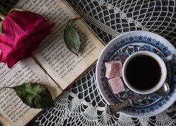 Filiżanka kawy i róża na otwartej książce