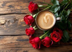 Filiżanka z kawą i róże na drewnianych deskach