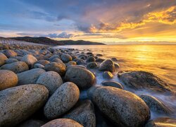 Kamienie na wybrzeżu morza w blasku wschodzącego słońca