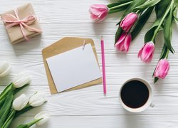 Kawa i kartka na kopercie pośród tulipanów