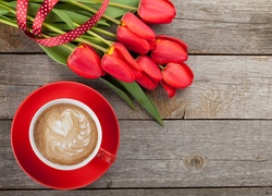Kawa w czerwonej filiżance obok bukietu tulipanów