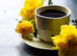 Kawa w filiżance obok żółtych róż