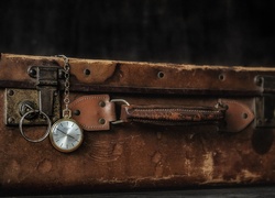 Kieszonkowy zegarek zwisający ze starej zniszczonej walizki