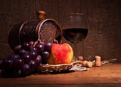 Kiść winogron,  jabłko i kieliszek z winem obok beczki w kompozycji