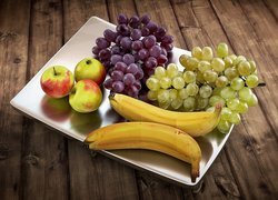 Kiście winogron, banany i jabłka na talerzu