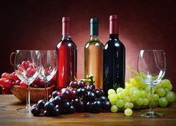 Kiście winogron obok butelek wina i kieliszków