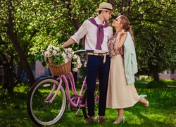 Kobieta i mężczyzna z rowerem i bukietem kwiatów w wiosennym ogrodzie