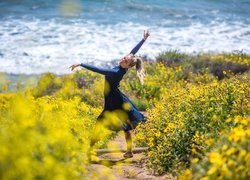 Kobieta tańcząca wśród kwiatów nad morzem