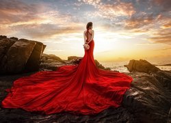 Kobieta w czerwonej sukni na skałach