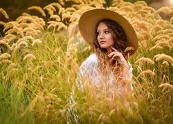 Kobieta w kapeluszu wśród wysokich traw