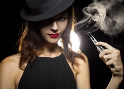Kobieta w kapeluszu z elektronicznym papierosem