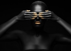 Kobieta w złotym makijażu zasłania twarz dłońmi