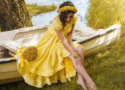 Kobieta w żółtej sukience siedzi na łódce