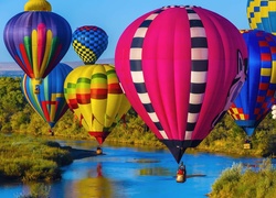 Kolorowe balony nad rzeką wśród drzew