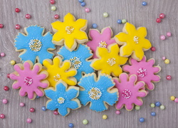 Kolorowe ciasteczka w kształcie kwiatków ułożone na drewnianym blacie
