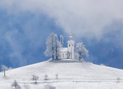 Kościół św Tomasza na ośnieżonym wzgórzu w słoweńskiej wsi Krivo Brdo