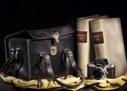 Książki obok aparatu fotograficznego i torby