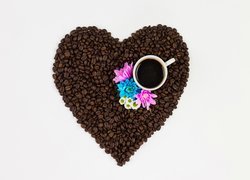 Kubek i kwiaty na ziarnach kawy w kształcie serca