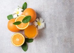 Kwiaty plumerii obok pomarańczy i soku w szklance