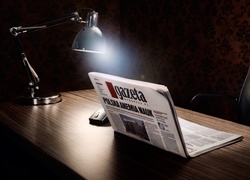 Lampka oświetlająca myszkę i gazetę ułożoną na kształt laptopa