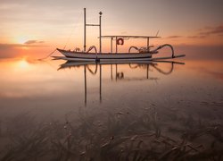 Łódka na morzu w blasku wschodzącego słońca