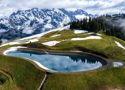 Małe jezioro i wyciąg narciarski na tle ośnieżonych gór