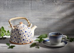 Malowany czajnik obok filiżanki herbaty