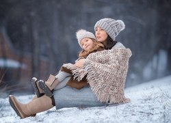 Matka z córką siedzące na śniegu