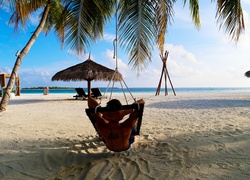 Mężczyzna wypoczywający na morskiej plaży pod palmami