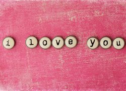 Miłosny napis z guzików na różowym tle