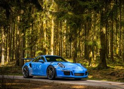 Niebieskie Porsche 911 GT3 na leśnej drodze