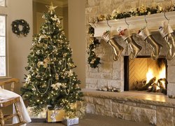 Oświetlona choinka z prezentami i świątecznie przystrojony kominek