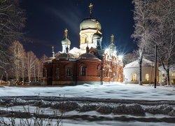 Oświetlona nocą cerkiew w zimowej scenerii