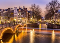 Oświetlony most i domy nad kanałem w Amsterdamie