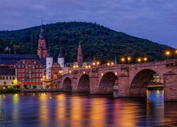 Oświetlony most i domy nad rzeką Neckar w Heidelbergu