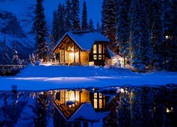 Oświetlony nocą dom w śniegu nad jeziorem Emerald Lake