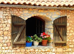 Otwarte okiennice i kwiaty w donicach na murku