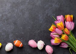 Pisanki i bukiet kolorowych tulipanów na ciemnym tle