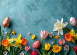 Pisanki i różnokolorowe kwiatki na niebieskim tle