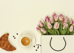 Rogalik z kawą obok tulipanów