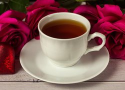 Róże i serduszko obok filiżanki herbaty